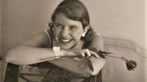 Sylvia Plath smiling with a rose in her right hand 