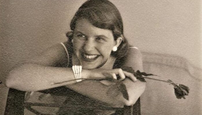 Sylvia Plath smiling with a rose in her right hand